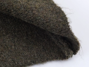 Vista macro della texture del tessuto a maglia verde scuro con morbide fibre di lana