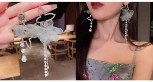 Detail of silver needle earrings with butterfly frame, grey silk flower and pearl tassels