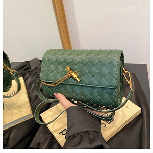 Detail of dark green woven crossbody bag featuring a golden twist-knot metal clasp