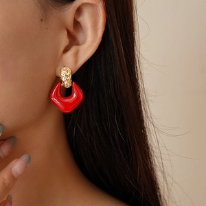 Close-up of model wearing geometric red enamel and hammered gold vintage earrings