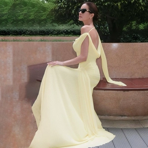 Outdoor side view of a pale yellow backless chiffon maxi dress with tie straps