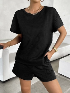 Detail of black knitted two-piece set featuring a unique diamond texture and a modern fit