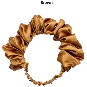 Detail of a brown satin ruched headband showing shiny pleated texture and elastic band