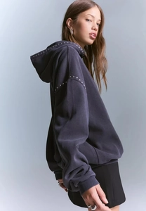 Detail of metal studs on the shoulder and hood of a dark grey-blue oversized hoodie