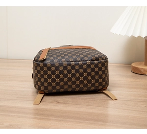 Detail view of the vintage brown patterned backpack on a wooden surface with soft lighting
