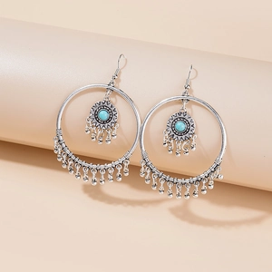 Detail of bohemian silver earrings with turquoise beads and feather tassel charms