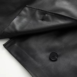 Macro view of black leather jacket detail showing round buttons and precise stitching
