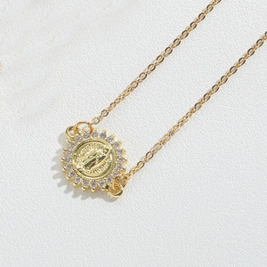 Close-up of golden Virgin Mary medal pendant with white zircon stones on a chain