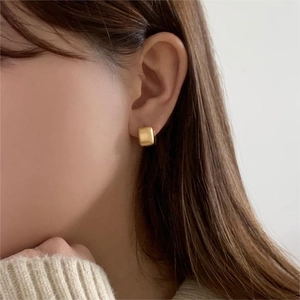 Close-up of matte brushed square earrings in gold on female model with minimalist style