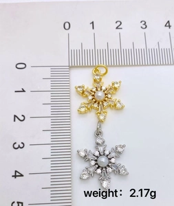 Macro shot of gold and silver snowflake charms with pearls and weight of 2.17g