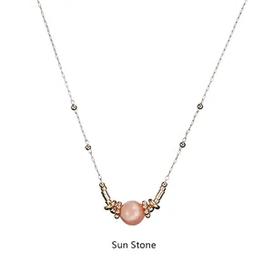 Close-up of a peach sunstone pendant necklace with golden metal beads and fine chain