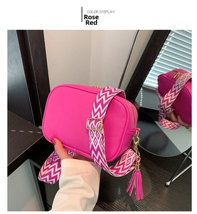 Dettaglio borsa in pelle grana litchi rosso rosa con tracolla a onde e nappa decorativa