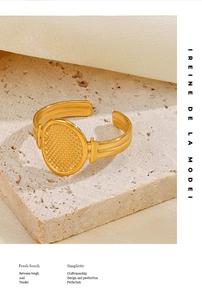 Detailed macro shot of oval gold-plated ring with intricate grid texture on stone base