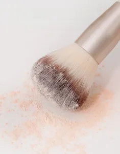 Dettaglio macro delle setole sfumate di un pennello trucco che cattura la polvere