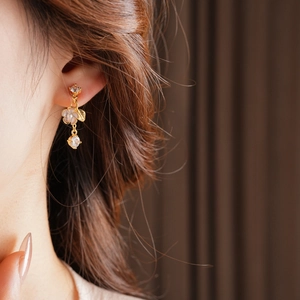 Detail of gold floral tassel earring with pearls on model for a vintage look
