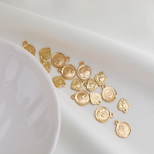 Detailaufnahme von 14K Gold gefüllten Herz- und Münzanhängern mit Queen Elizabeth II Gravur