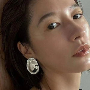 Macro shot of silver irregular oval metal earrings with a wrinkled metallic texture
