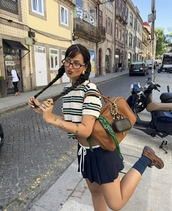 Scatto street style di una polo a righe retrò con gonna a pieghe e borsa a tracolla moda
