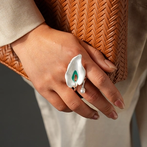 Detailed view of floral enamel ring with green core and pearls worn on finger