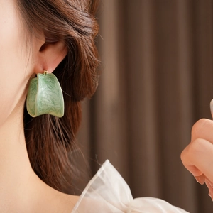 Close-up of green marble effect C-shaped acrylic hoop earrings on model