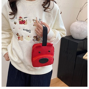 Detail of red cartoon bear handbag with black handles and three-dimensional ear design