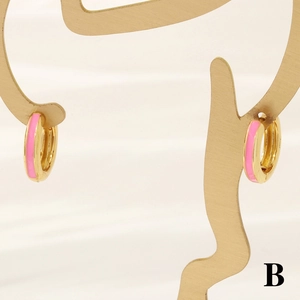 Macro view of 18K gold-plated hoop earrings with vibrant pink enamel on a jewelry stand