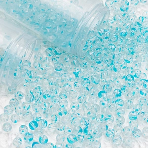 Macro view of blue spotted glass beads spilling from clear tubes for DIY jewelry