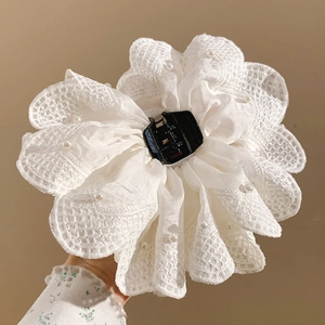 Close-up of white fabric flower hair claw with lace trim and elegant imitation pearls