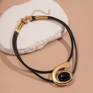 Détail du collier bohème double cordon noir avec un pendentif en spirale dorée