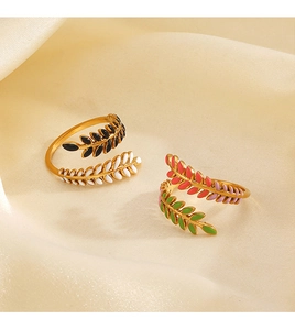 Macro shot of gold leaf rings with colorful enamel inlay on beige silk fabric