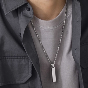 Detail shot of a rectangular 3D bar pendant necklace in silver stainless steel on a model