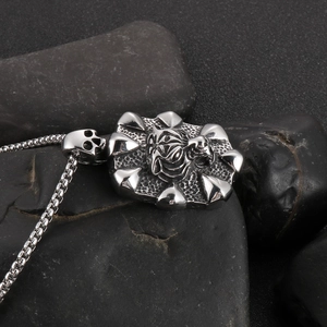 Detailed close-up of tiger head and skull pendant on silver box chain necklace