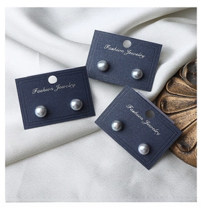 Macro shot of three pairs of grey freshwater pearl stud earrings on white silk fabric