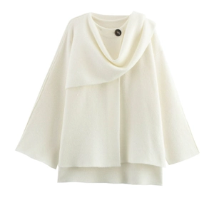 Dettaglio ravvicinato di poncho in maglia bianca con ampio colletto e bottone scuro