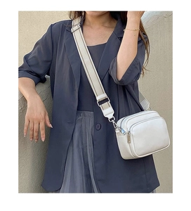Detail view of the white crossbody bag with twin zipper pockets and wide canvas shoulder strap