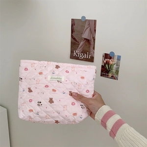 Close-up of pink quilted makeup bag with cute rabbit patterns and brand label