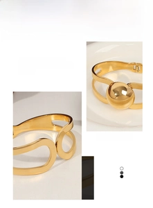 Detail of gold-plated geometric hollow bangle with a polished metal bead on white ceramic