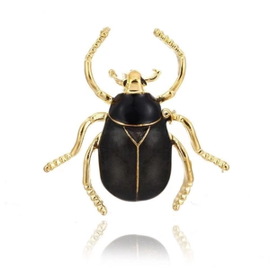 Golden beetle brooch featuring polished black enamel shell on a white background