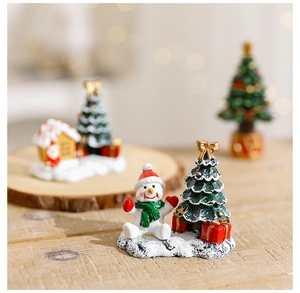 Detailed view of a resin Christmas snowman and tree ornament on a snowy base