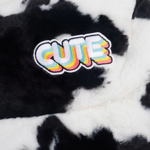 Gros plan sur la texture en fausse fourrure et l'écusson brodé CUTE du chapeau