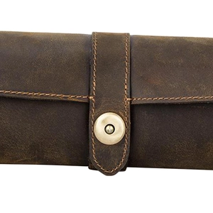 Detailed close-up of retro leather watch roll with metal snap buckle and fine stitching