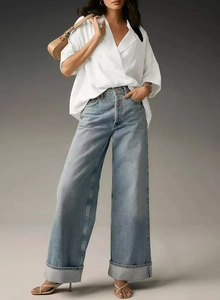Detail of high-waist wide-leg denim jeans with white shirt and camel underarm bag