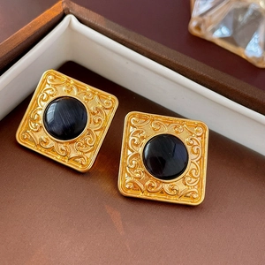 Macro shot of vintage black and gold square earrings with cat eye stone and floral carving