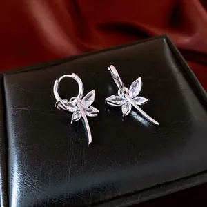 Elegant silver dragonfly earrings with marquise-cut zircons on a luxury silk background