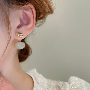 Gros plan de boucles d'oreilles ovales plaquées or avec pendentif émail beige sur mannequin