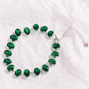 Detail of green zircon silver bracelet with adjustable pink stone charm on textured paper