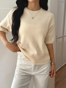 Minimalist beige round neck knit sweater for women shown on a model in a bright setting