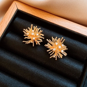 Detail view of 18k gold plated firework stud earrings with zircons on black velvet tray