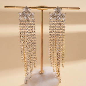 Detailed close-up of golden tassel earrings with sparkling rhinestones on a jewelry stand