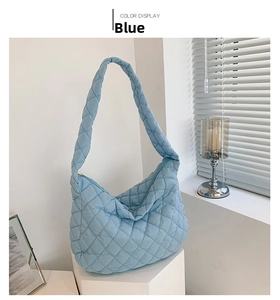 Detail view of the quilted rhombic pattern on a large blue padded shoulder bag